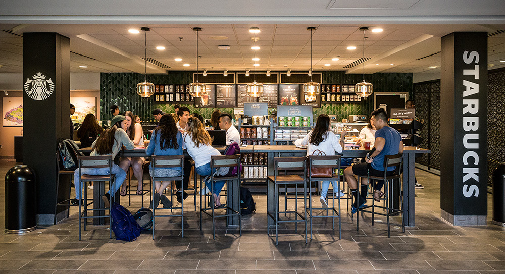 Customers seated at a communal table in a Starbucks coffee house