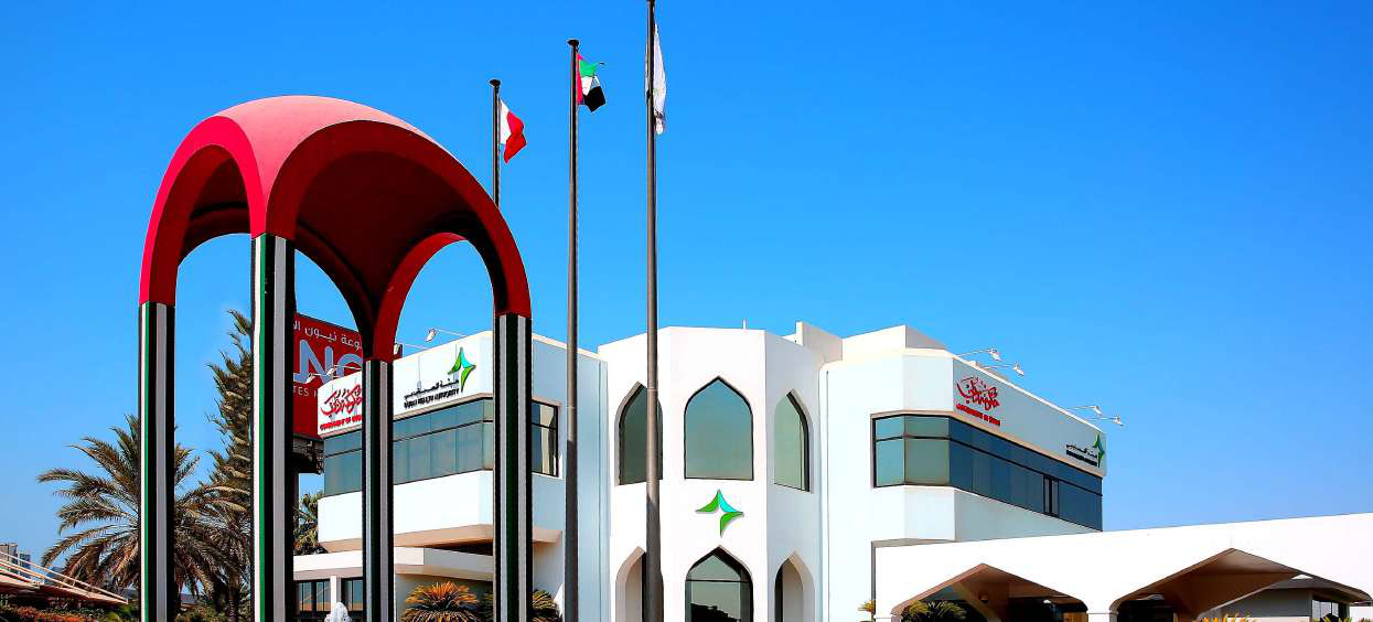 Exterior of a Dubai Health Authority facility with UAE flags and the DHA emblem