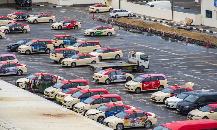 Aerial view of a Dubai taxi depot with rows of cream and red RTA taxis