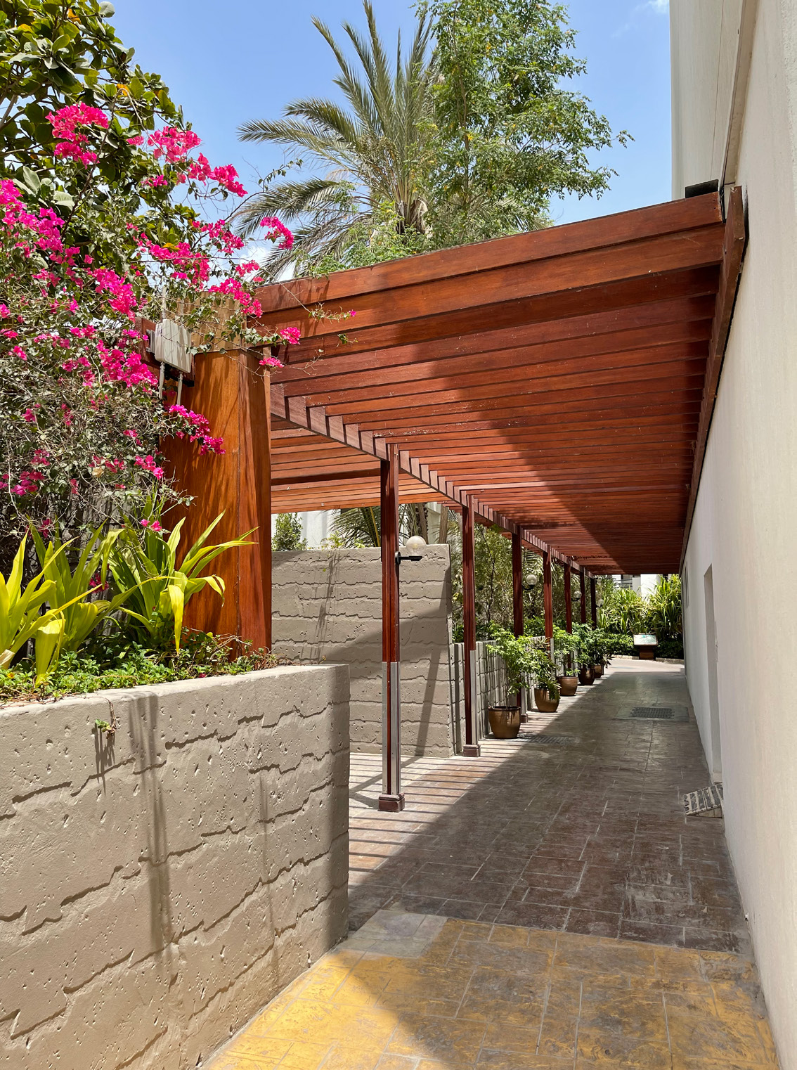 Covered walkway at the resort with a wall-mounted enclosure above the timber pergola