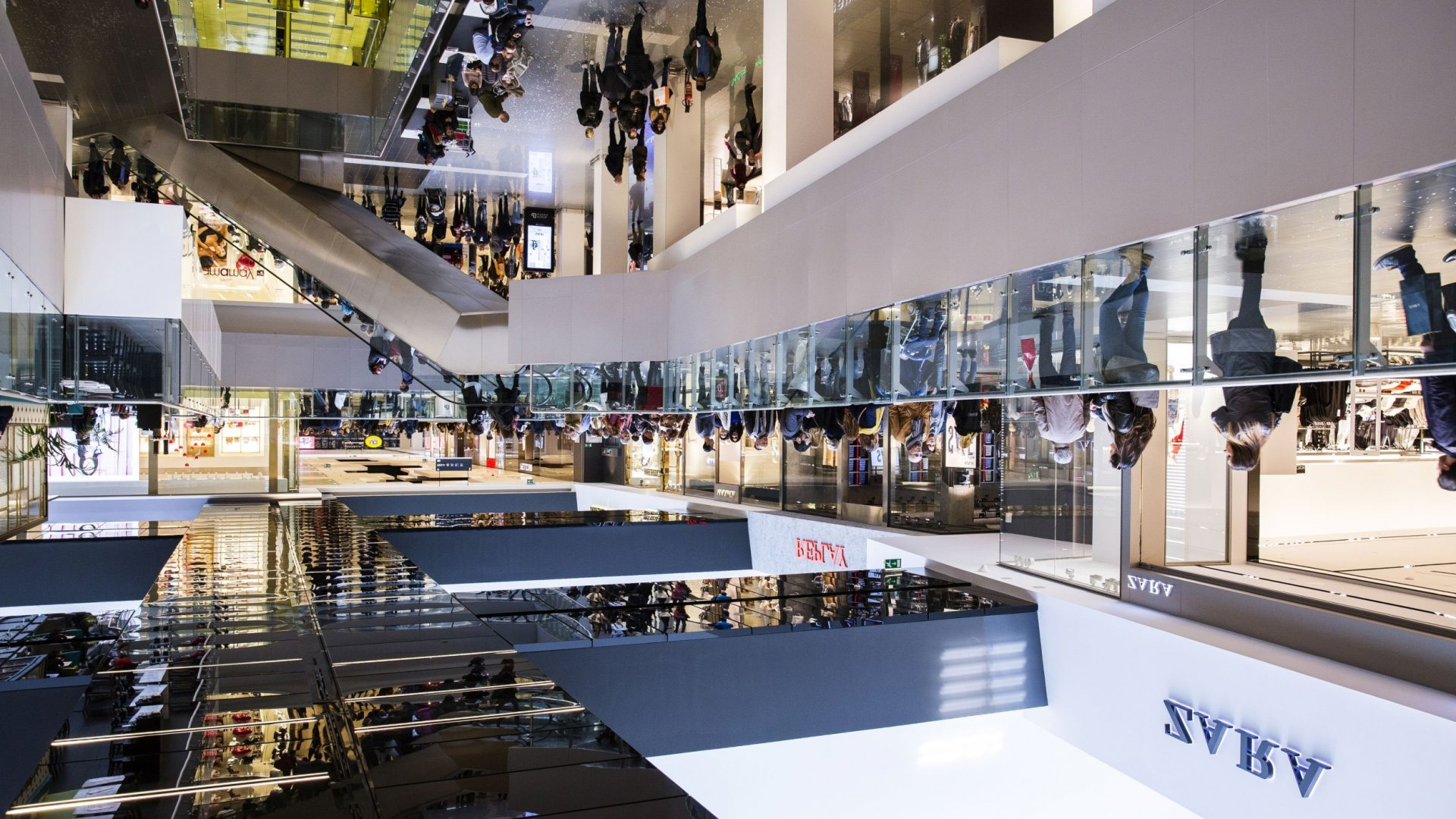 Busy multi-level shopping mall atrium in Dubai with shoppers on escalators