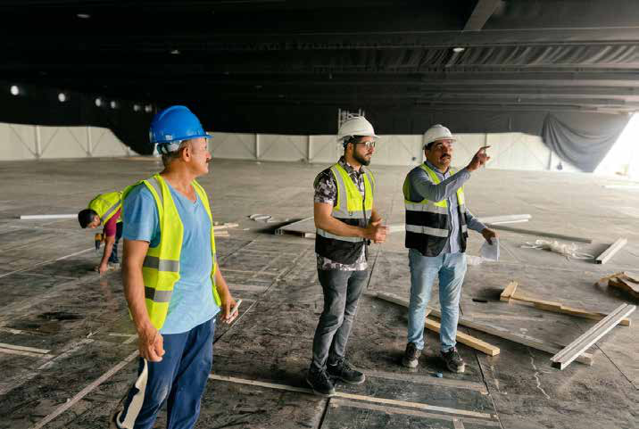 EZELINK engineers surveying a bare festival venue during fit-out, wearing hard hats and hi-vis